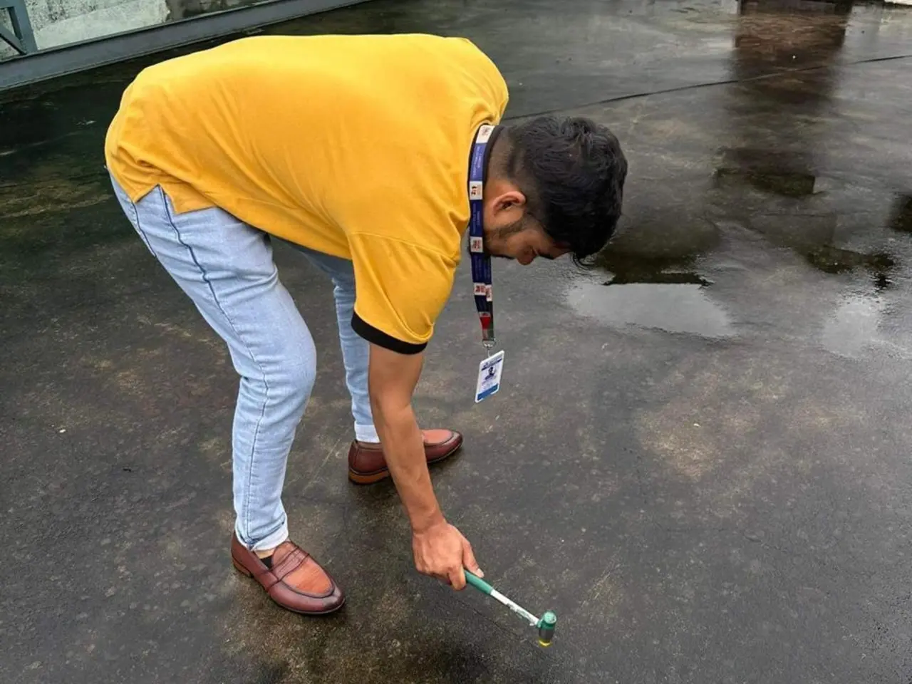 using a specialized hammer to inspect a damp concrete roof surface for cracks or hollow spots