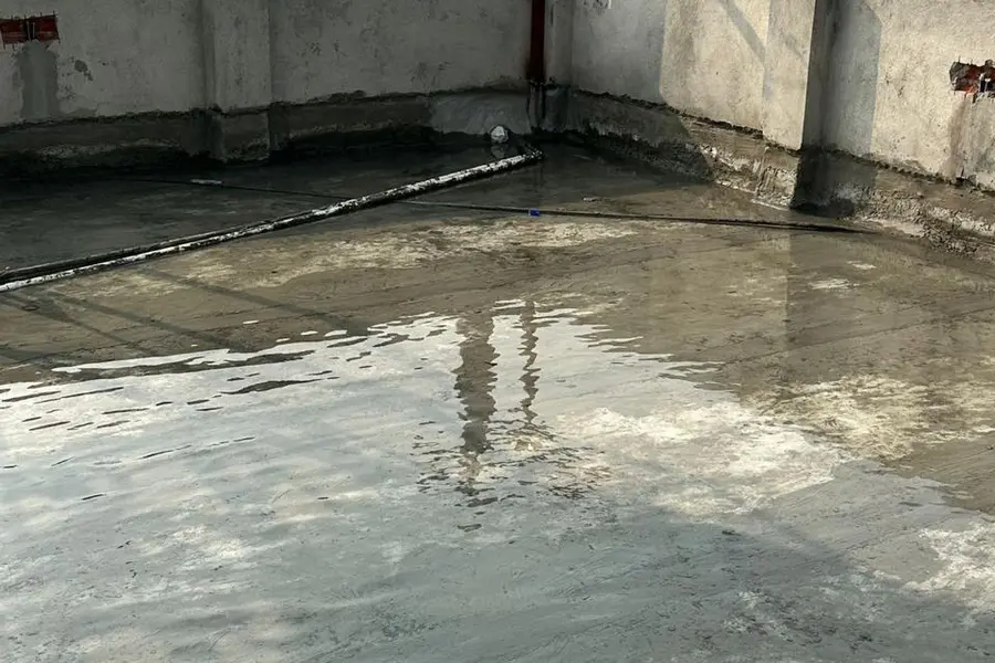 Concrete rooftop surface prepared for waterproofing with parapet walls and water tank in the background in Nepal.